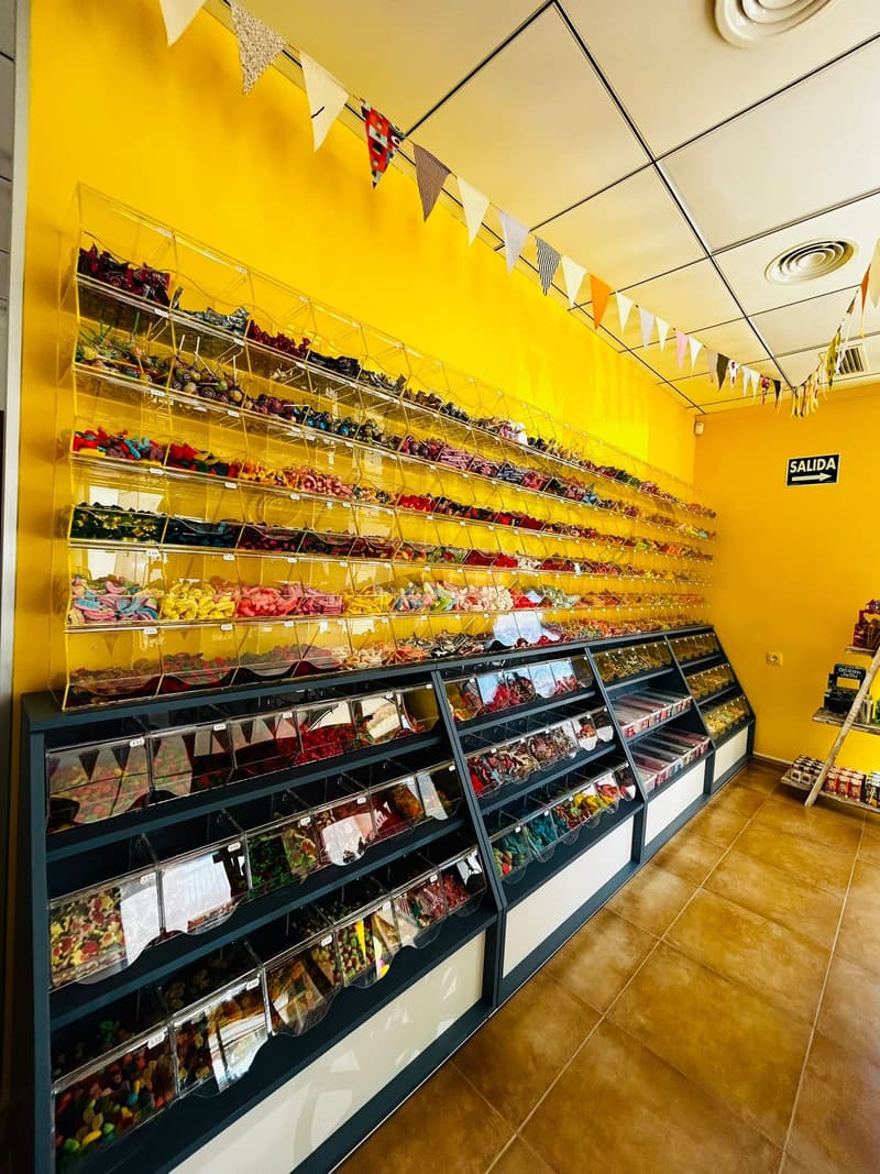 Pared amarilla de la tienda llena de dispensadores de chuches a granel