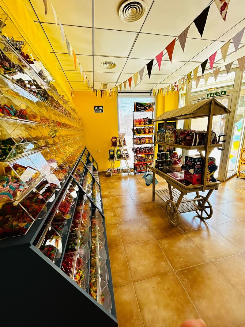Pasillo de la tienda con el muro de chuches y banderines en el techo